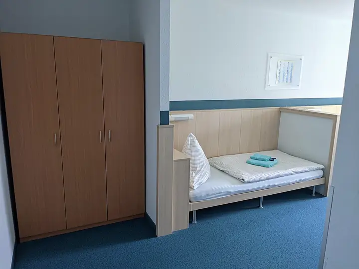 Kamar sederhana dengan ranjang tunggal dan lemari pakaian