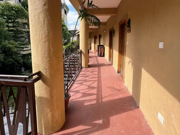 Selasar lantai 2 beratap dengan pagar balkon dan deretan pintu kamar